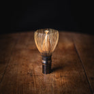 Wooden whisk on a wooden surface with a dark background